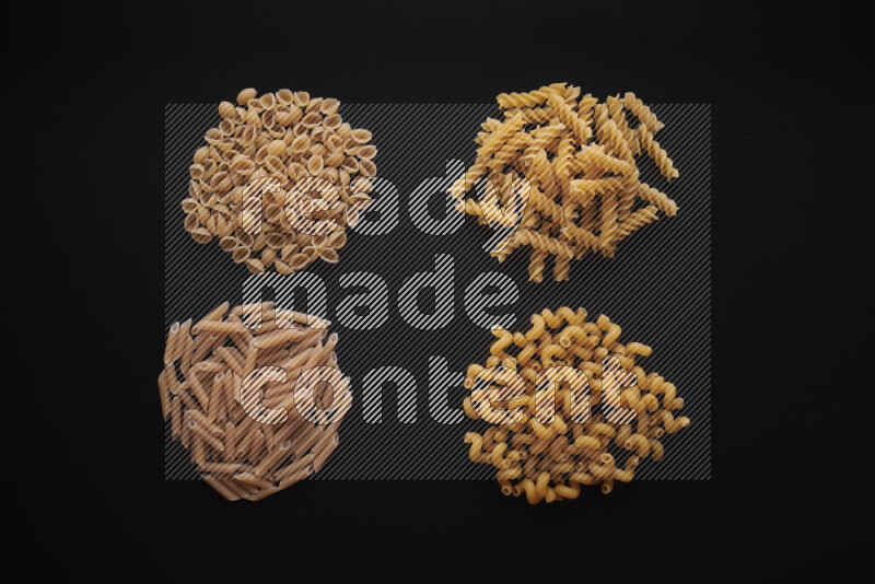 Different pasta types in bunches on black background