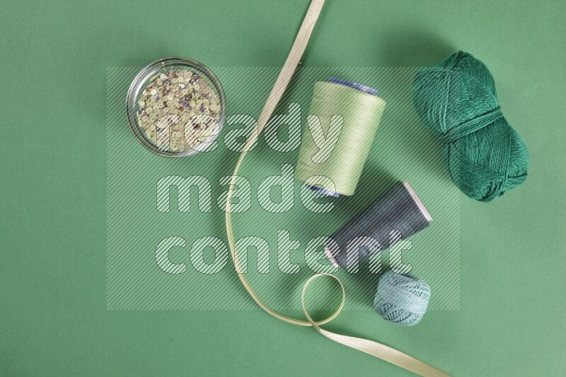 A green collection of sewing and tailoring tools arranged on a green background