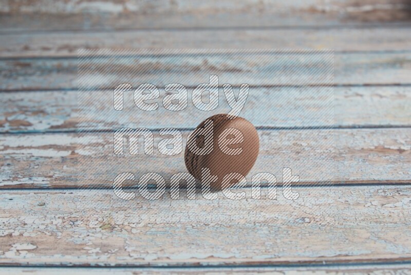 45º Shot of Brown Dark Chocolate macaron on light blue wooden background