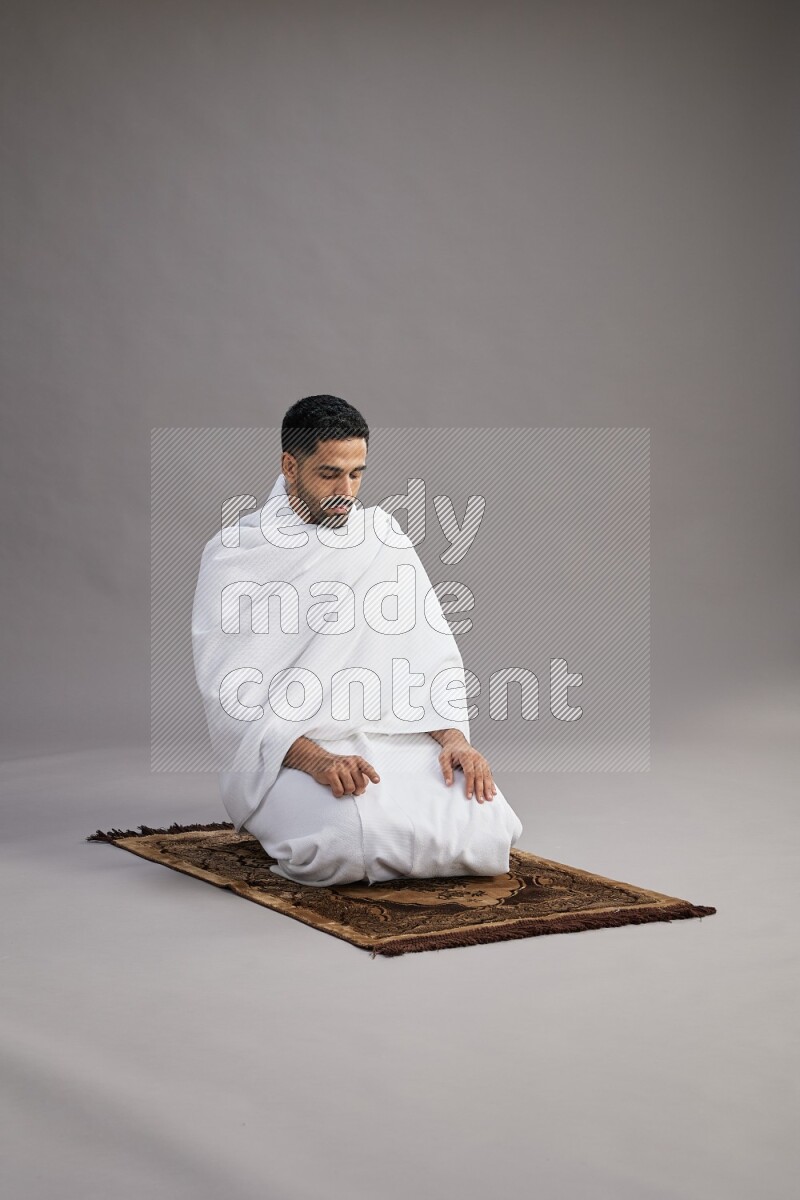 A man wearing Ehram praying on gray background