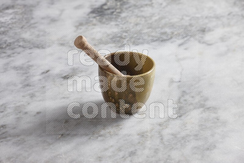 Multicolored pottery cup with wooden honey dipper in it on grey marble background