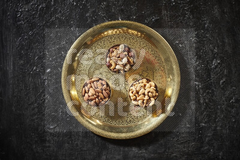 Nuts in metal bowls on a tray in a dark setup