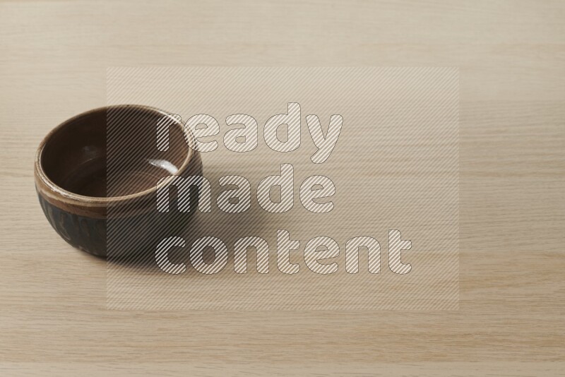 A multicolored pottery bowl on light wooden background