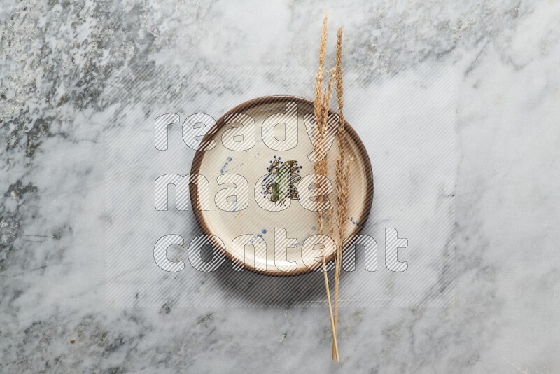 Wheat stalks on decorative pottery plate on grey marble background