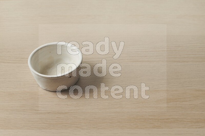 A white pottery bowl on light wooden background