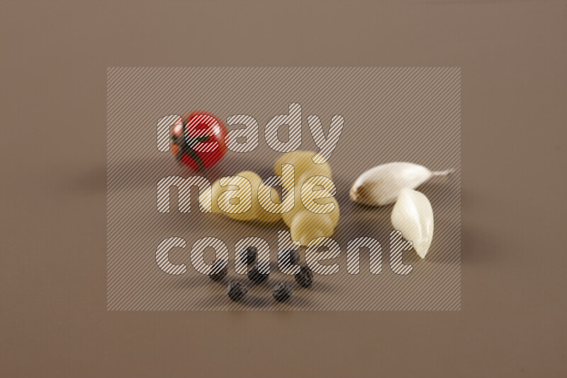 Raw pasta with different ingredients such as cherry tomatoes, garlic, onions, red chilis, black pepper, white pepper, bay laurel leaves, rosemary and cardamom on beige background