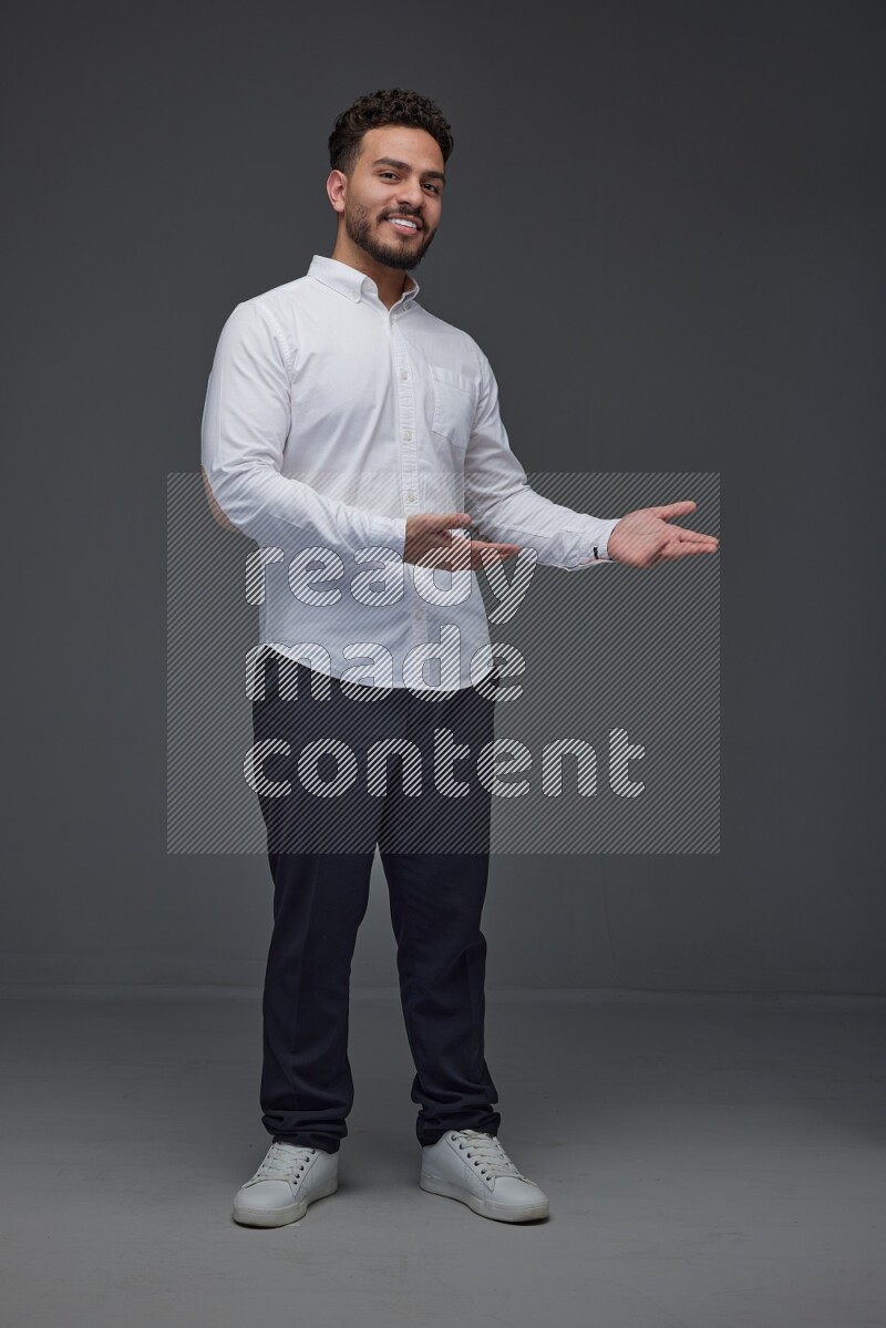 A man wearing smart casual standing and making multi hand gestures eye level on a gray background