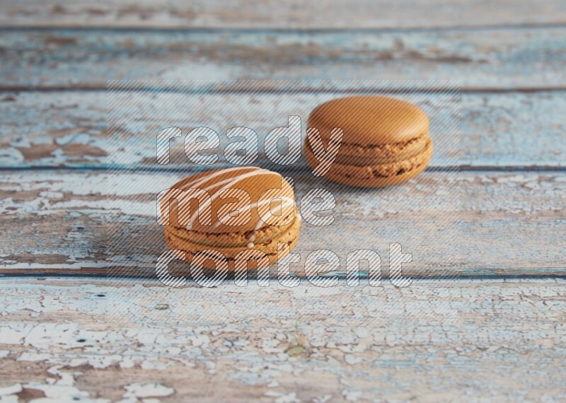 45º Shot of of two assorted Brown Irish Cream, and Brown Maple Taffy macarons  on light blue background