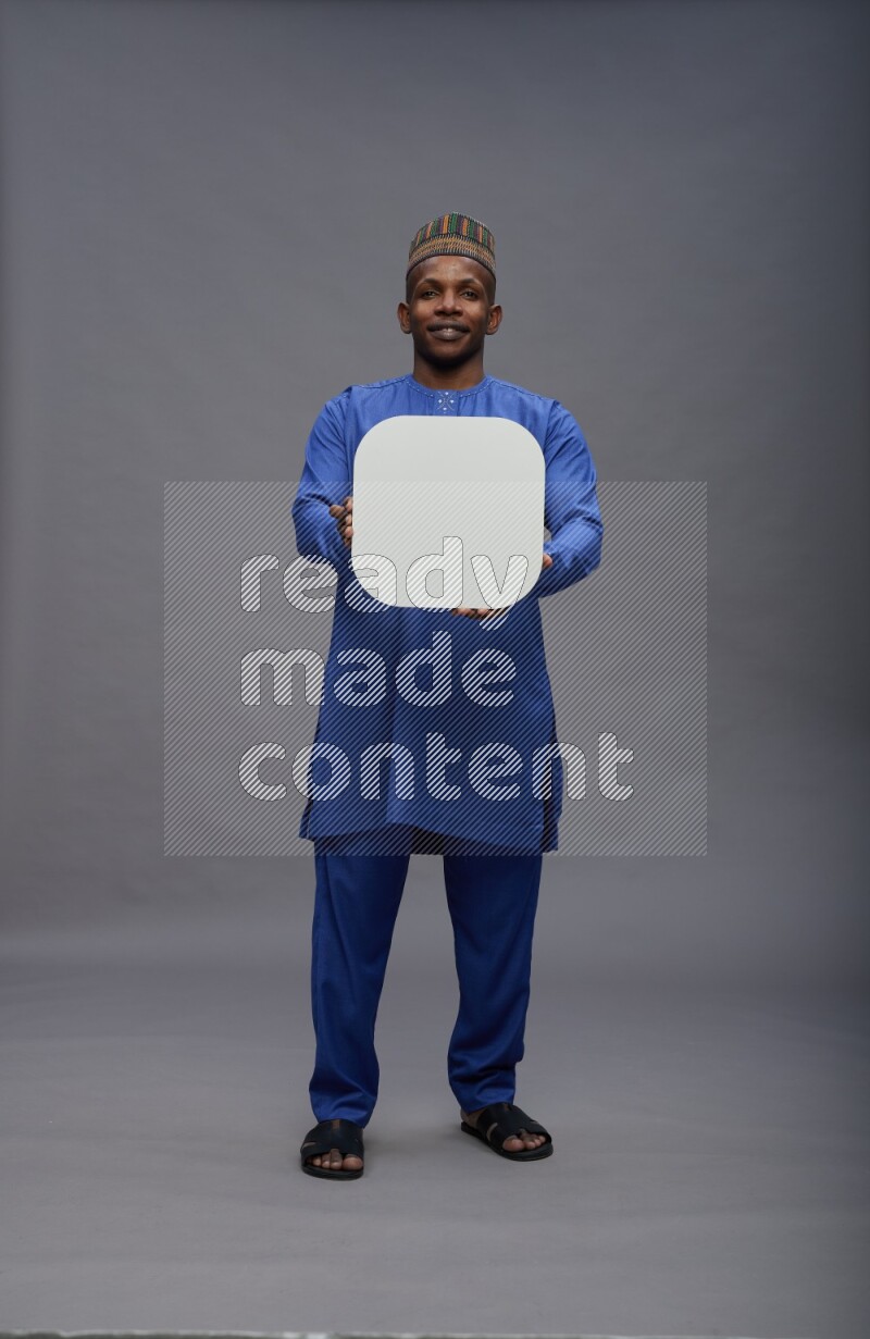 Man wearing Nigerian outfit standing holding social media sign on gray background