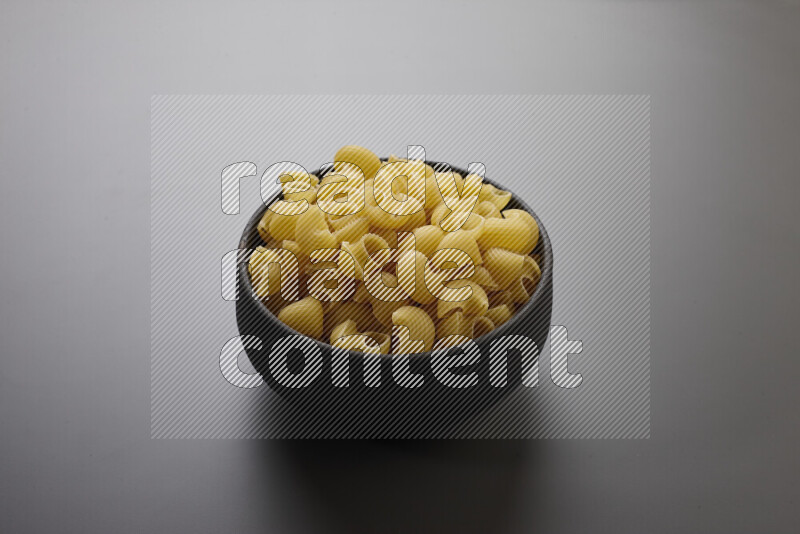 Pipe pasta in a pottery bowl on grey background