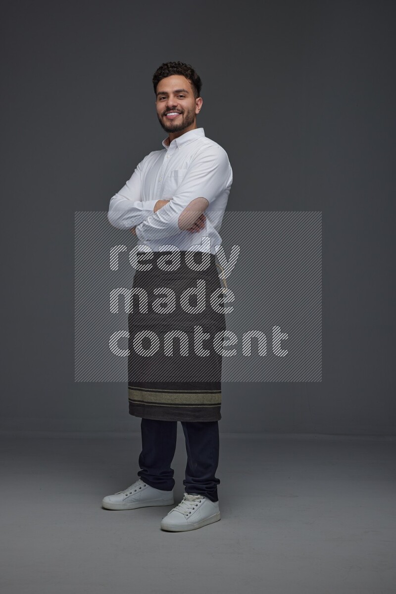 A man wearing smart casual and apron standing and making multi poses eye level on a gray background