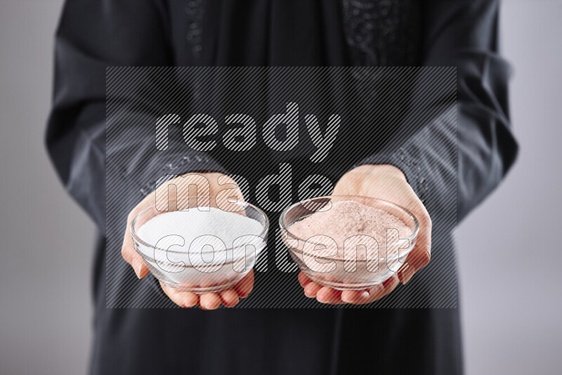 Woman in abaya holding different kinds of spices in different positions