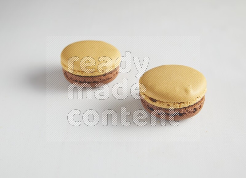 45º Shot of two Yellow and Brown Chai Latte macarons on white background