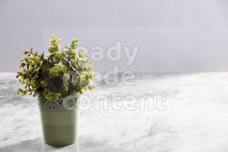Artificial plant in green decorative pot on grey marble background
