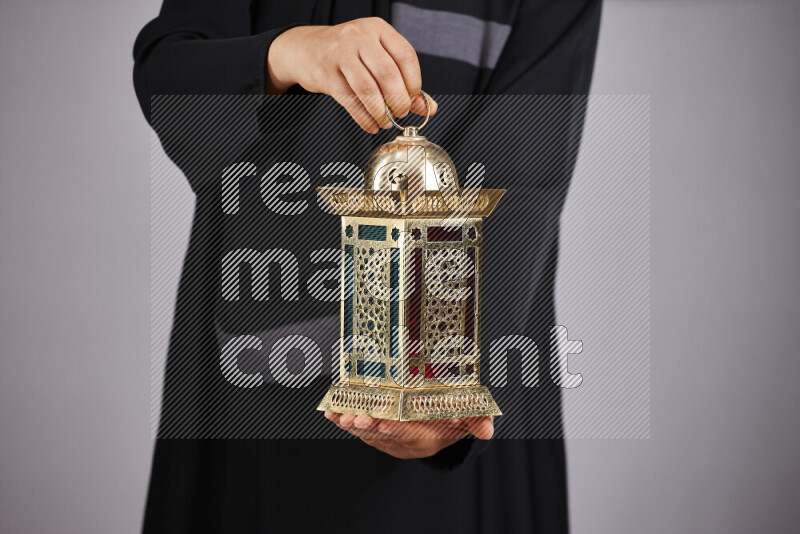 A woman in black abaya holding different ramadan lanterns in different positions
