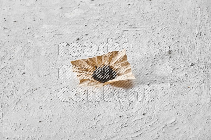 Black pepper on a crumpled paper on a textured white flooring