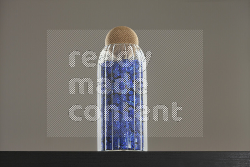 Sequins in a glass jar on black background