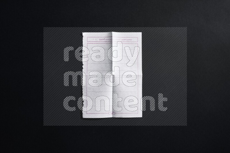 Folded notebook sheet on black background
