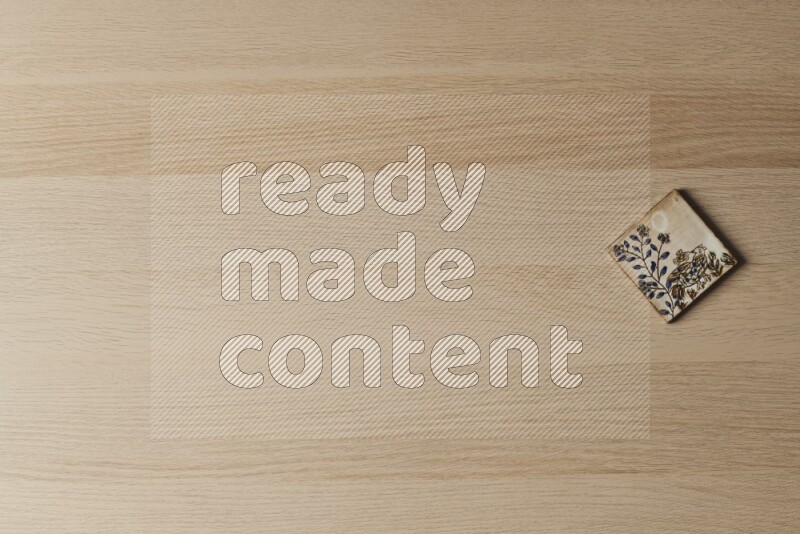 A decorative pottery coaster on light wooden background