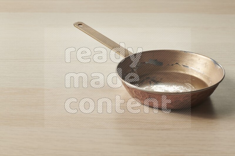 A small copper pan on light wooden background
