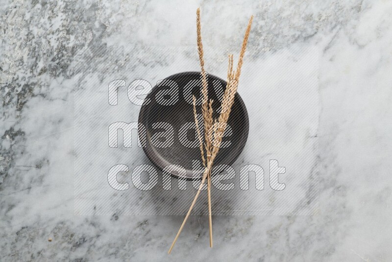 Wheat stalks on black pottery oven plate on grey marble background