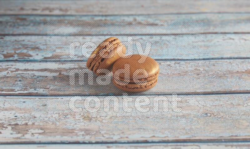 45º Shot of two Brown Coffee macarons on light blue wooden background