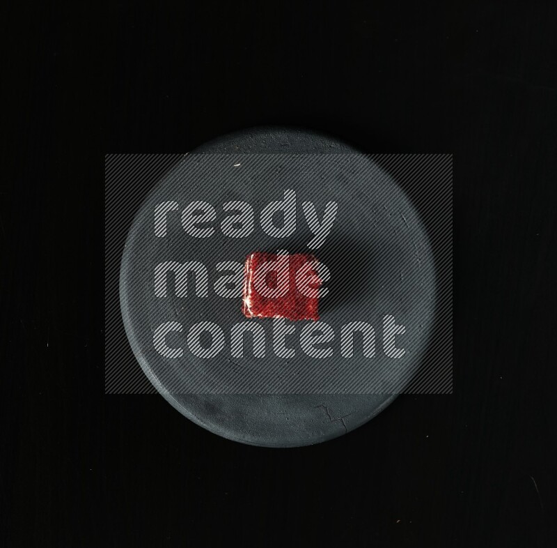 Assorted desserts in a black pottery plate on black background