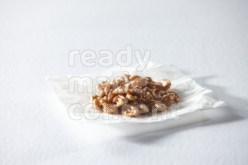 Peeled walnuts on a crumpled piece of paper on a white background in different angles