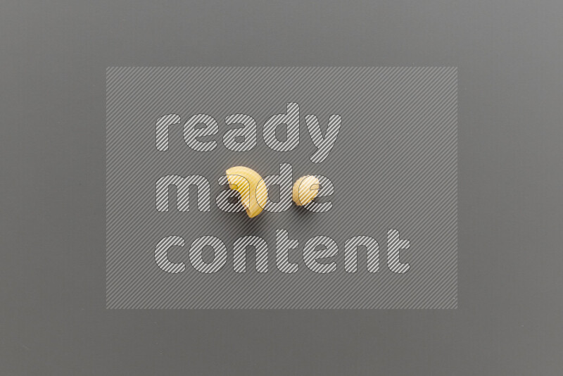 Elbow pasta with other types of pasta on grey background