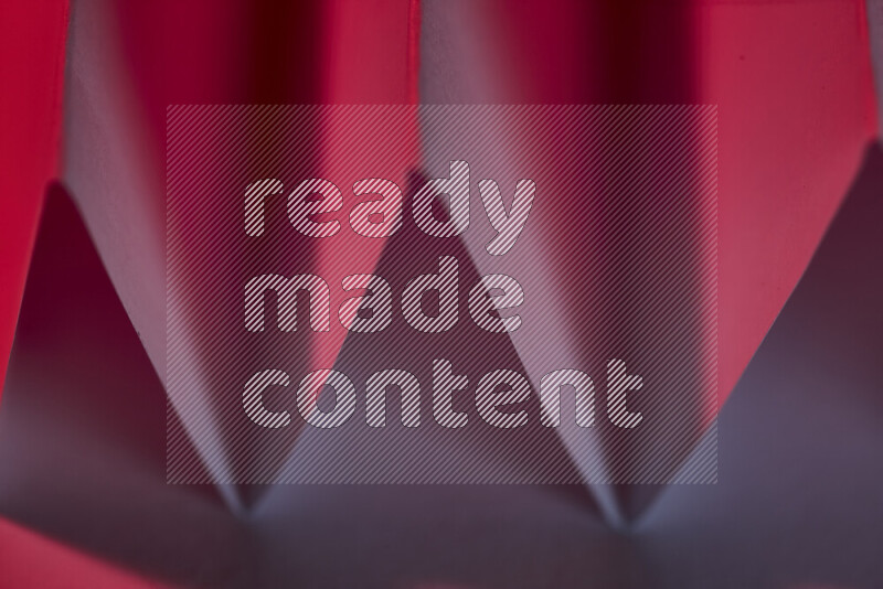 صورة مجردة مقربة تظهر طيات ورقية هندسية حادة بتدرجات اللون الأحمر