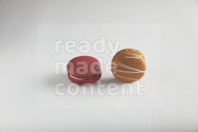 45º Shot of of two assorted Brown Irish Cream, and Red Velvet macarons on white background