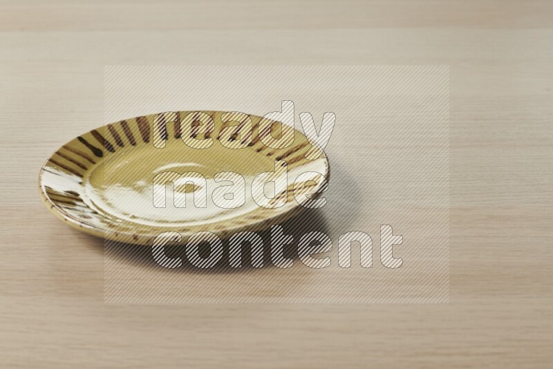 A multicolored pottery plate on light wooden background