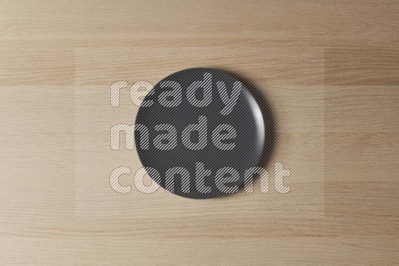 A black ceramic circular plate on light wooden background