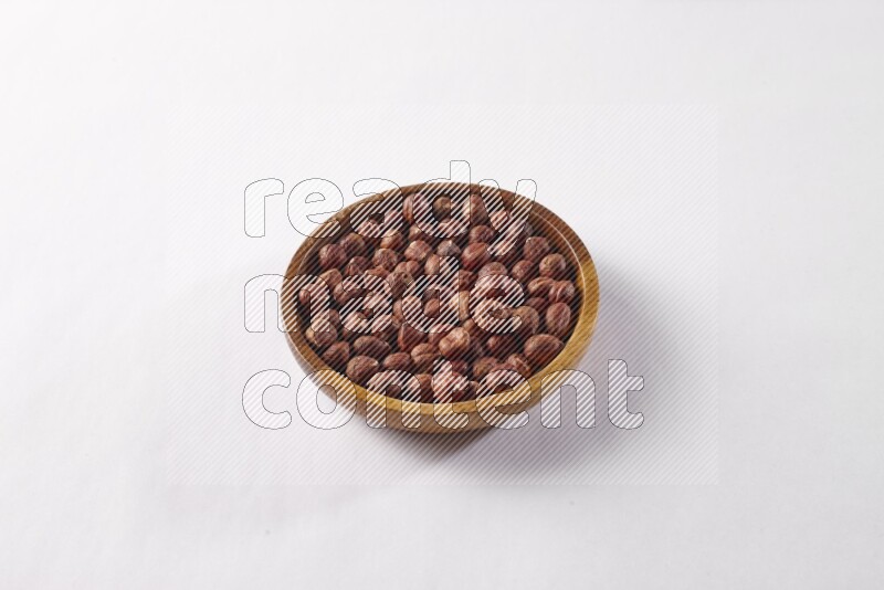 Hazelnuts in a wooden bowl on white background