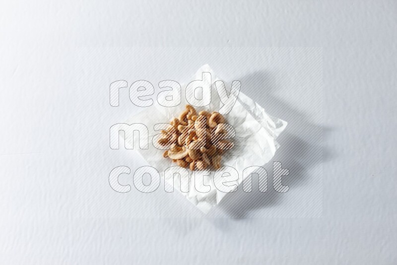 Cashews on a crumpled piece of paper on a white background in different angles