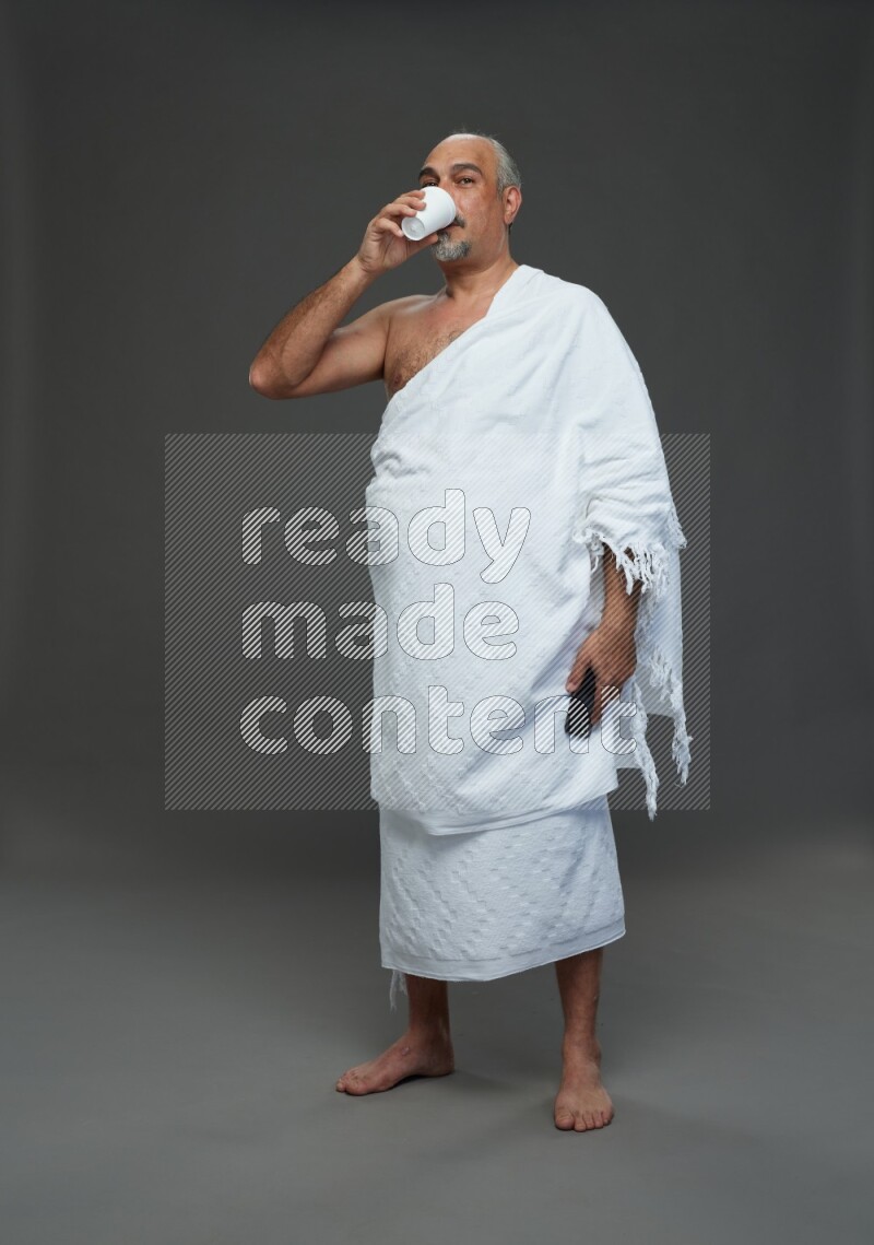 A man wearing Ehram Standing taking selfie on gray background