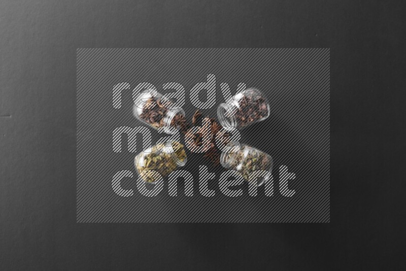 قرنفل وحبوب الهيل وريحان مجفف ويانسون نجمي في أوعية زجاجية علي خلفية سوداء