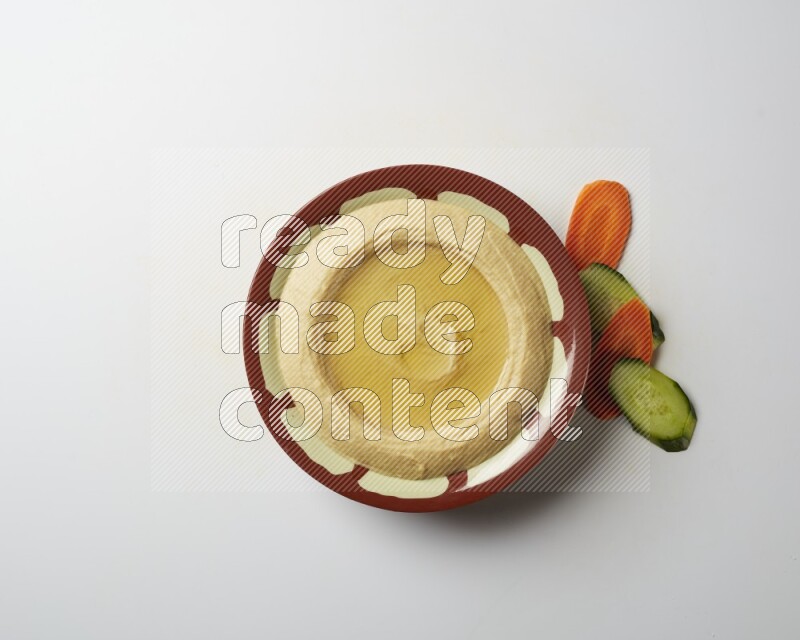 Hummus in a traditional plate garnished with olive oil on a white background