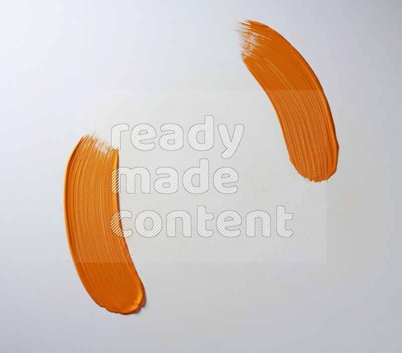 An orange curved painting brush stroke on a white background