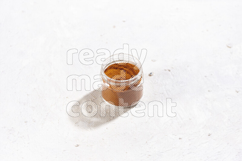 A glass jar full of ground paprika powder on white background