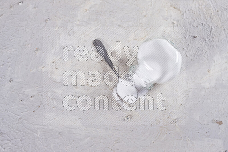A glass jar full of fine table salt on white background