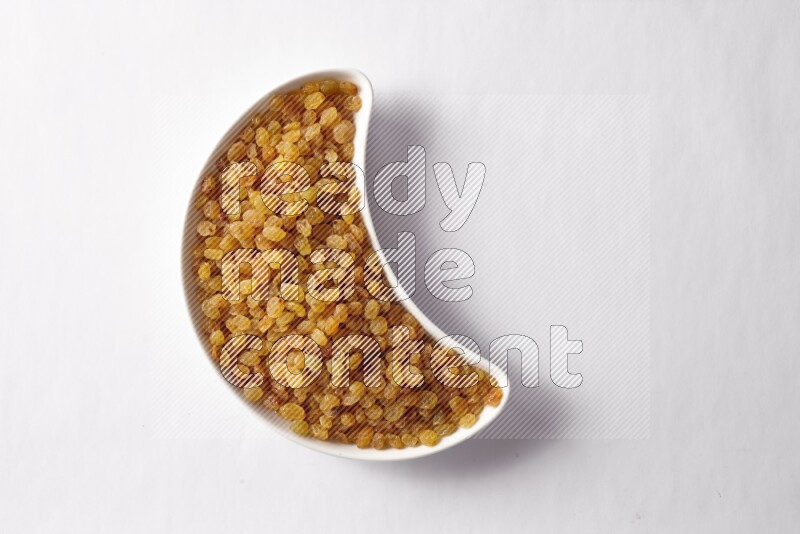Raisins in a crescent pottery plate on white background