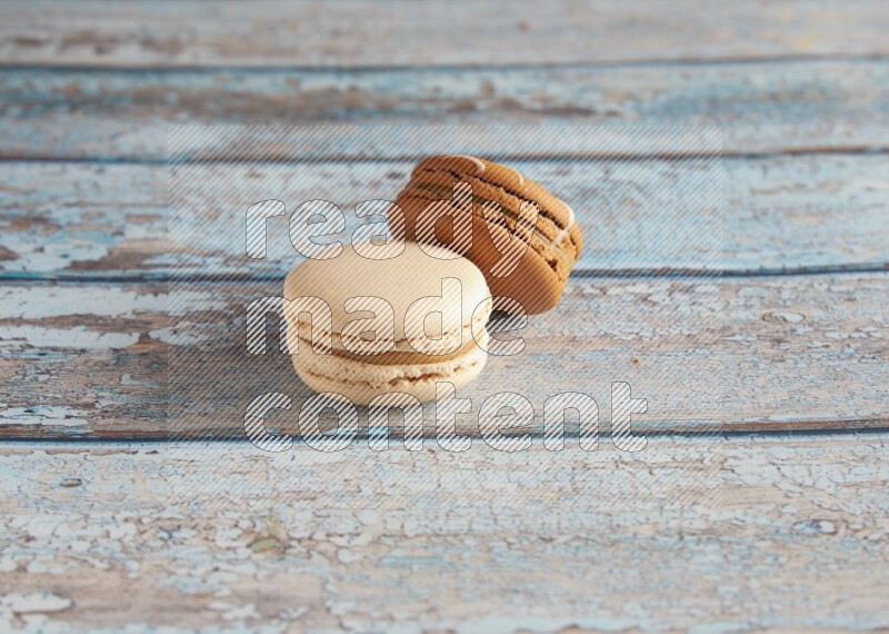 45º Shot of of two assorted Brown Irish Cream, and White Caramel fleur de sel macarons on light blue background