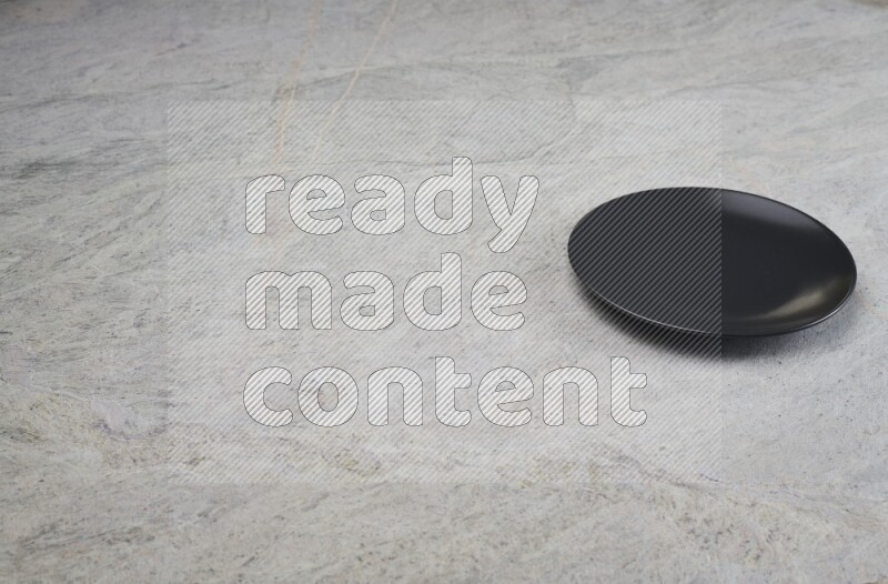 A black ceramic circular plate on grey marble background