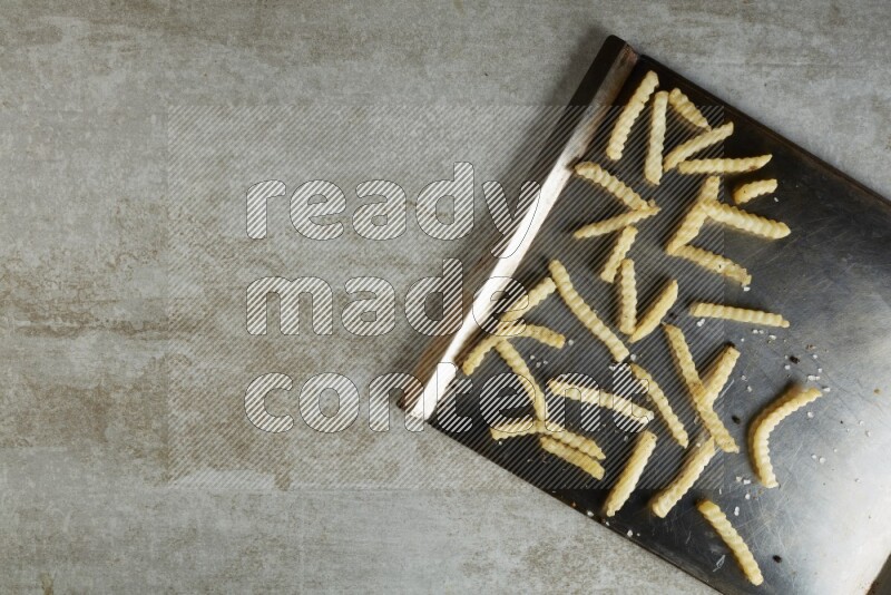 crinkle fries in a black stainless steel rectangle tray on grey textured counter top