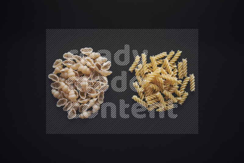 Different pasta types in bunches on black background