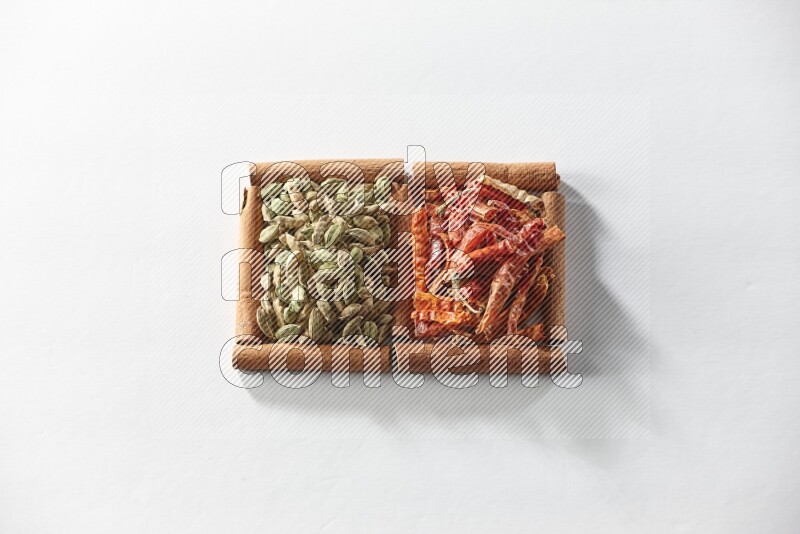 2 squares of cinnamon sticks full of cardamom and dried red chilis on white flooring