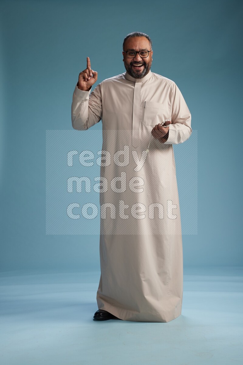 Saudi Man without shimag Standing Interacting with the camera on blue background