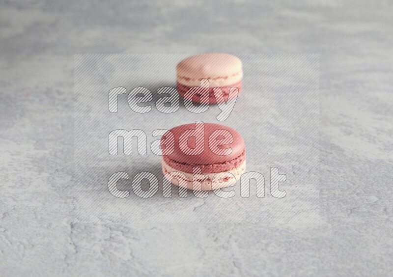 45º Shot of two Pink Litchi Raspberry macarons  on white  marble background