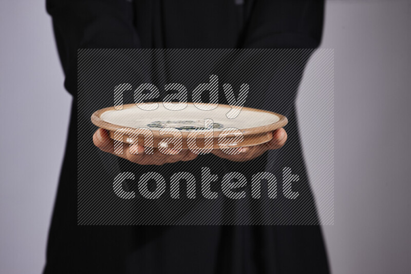 A woman in black abaya holding different pottery essentials in different positions